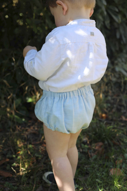 loomer en lin bleu avec bretelles amovibles et boutons en coco – vêtement bébé et enfant élégant et confortable, idéal pour les cérémonies et les journées ensoleillées.